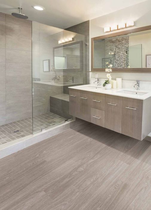 bathroom with waterproof luxury vinyl floors, double vanity and custom tile shower